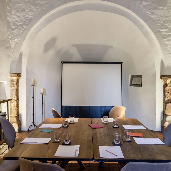 Moderner Meetingraum mit Tischen, Stühlen, Notizblöcken und Projektionswand