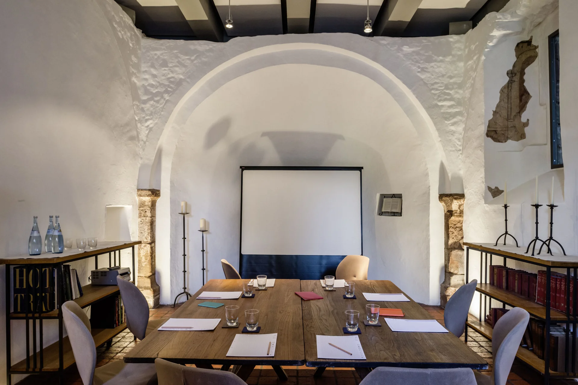 Moderner Meetingraum mit Tischen, Stühlen, Notizblöcken und Projektionswand