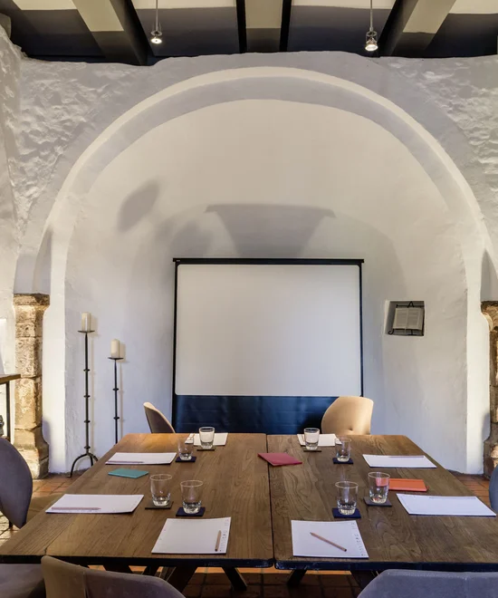 Moderner Meetingraum mit Tischen, Stühlen, Notizblöcken und Projektionswand