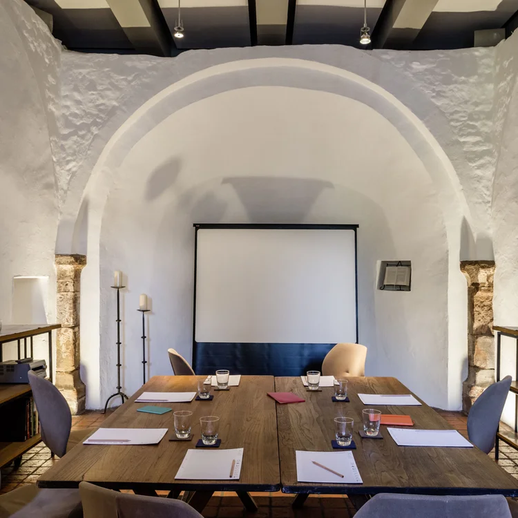 Moderner Meetingraum mit Tischen, Stühlen, Notizblöcken und Projektionswand