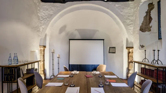 Moderner Meetingraum mit Tischen, Stühlen, Notizblöcken und Projektionswand