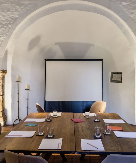 Moderner Meetingraum mit Tischen, Stühlen, Notizblöcken und Projektionswand