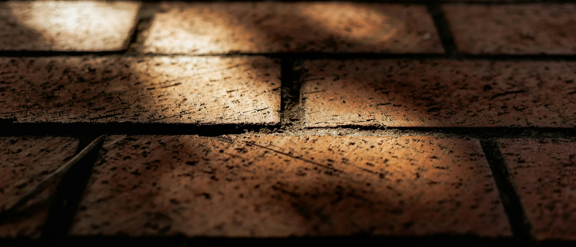 Nahaufnahme einer sonnendurchfluteten roten Backsteinmauer mit Schatten