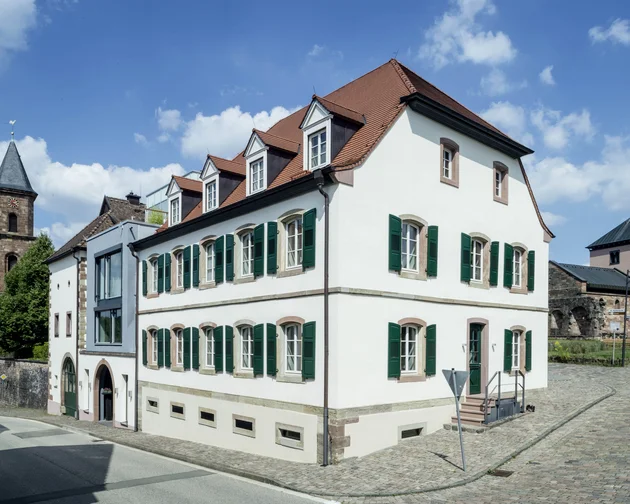 Treffpunkt, Kraftplatz und Hotel in Hornbach Historisches weißes Gebäude mit grünem Fensterläden in alter Stadt bei Sonnenschein