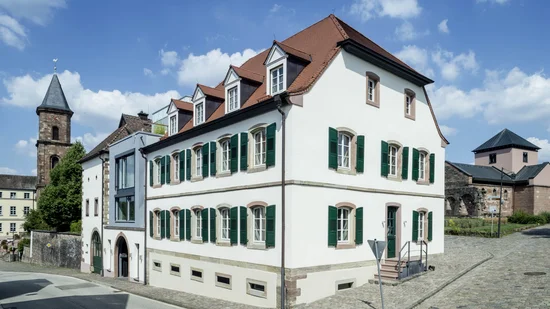 Historisches weißes Gebäude mit grünem Fensterläden in alter Stadt bei Sonnenschein