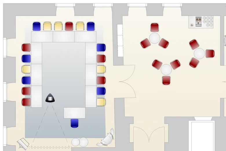 Raumplan mit U-förmiger Tischanordnung und mehreren Stühlen in verschiedenen Farben