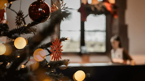 Weihnachtsbaum mit roten und goldenen Ornamenten, unscharfe Person im Hintergrund