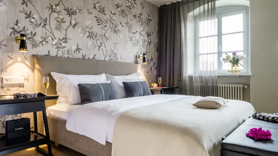 Modernes Schlafzimmer mit floralem Tapetenmuster, großem Bett und Fenstervorhängen