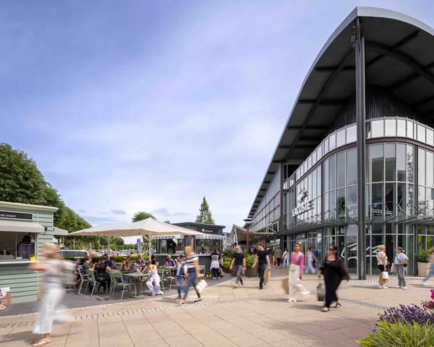 Außenbereich eines Einkaufszentrums mit Lacoste-Geschäft und Menschen im Freien