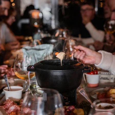 Menschen essen gemeinsam Fondue an festlich gedecktem Tisch