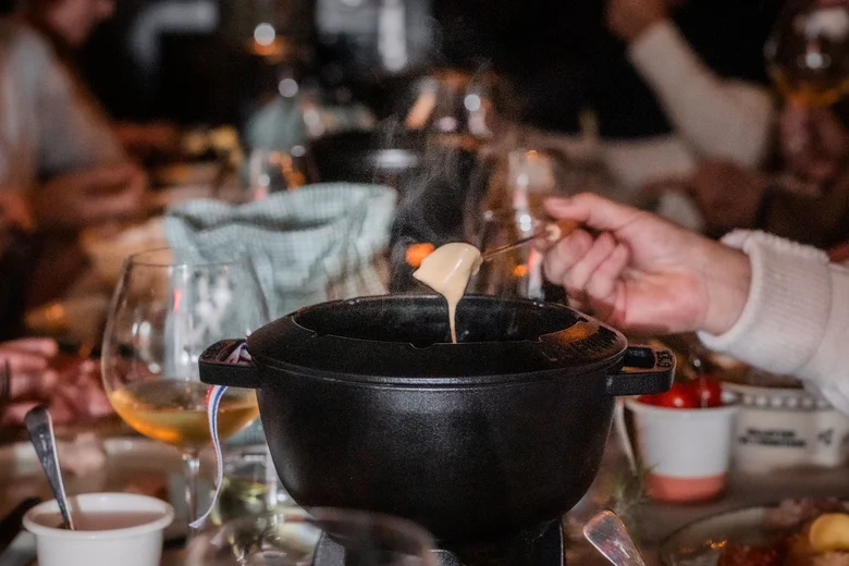 Menschen essen gemeinsam Fondue an festlich gedecktem Tisch