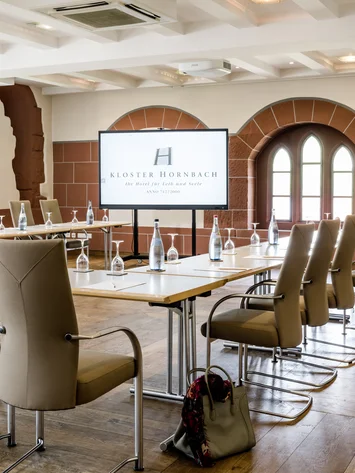 Moderner Konferenzraum mit Bildschirm und bestuhltem Tisch in Kloster Hornbach