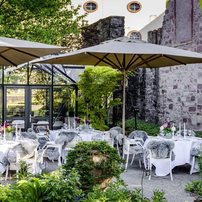 Elegante Außenterrasse mit Tischen unter Sonnenschirmen und dekorativer Bepflanzung