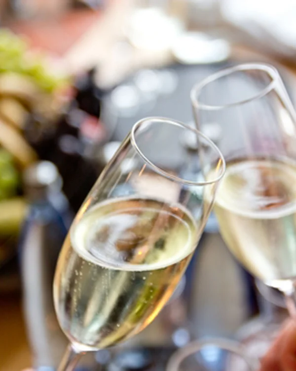 Zwei Sektgläser beim Anstoßen mit unscharfem Hintergrund