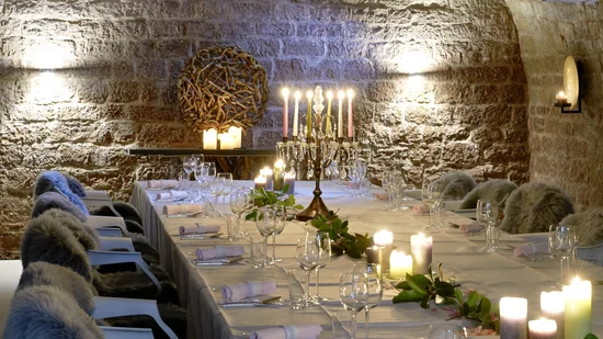 Eleganter Tisch in einem steinernen Gewölbekeller mit Kerzen und Fellen