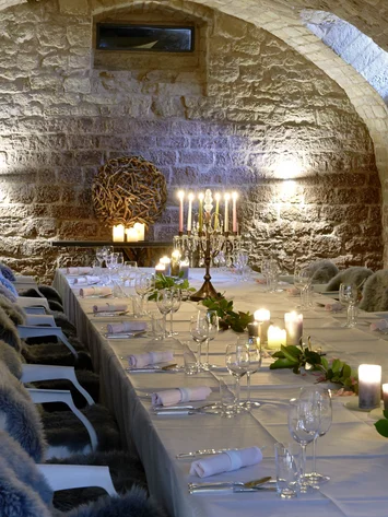 Eleganter Tisch in einem steinernen Gewölbekeller mit Kerzen und Fellen