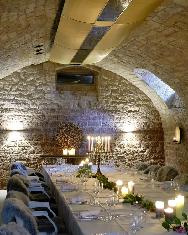 Fancy booking the entire country house? Elegant table in a stone vaulted cellar with candles and fur-covered chairs