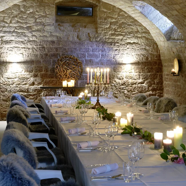 Eleganter Tisch in einem steinernen Gewölbekeller mit Kerzen und Fellen