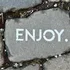 Stein mit dem Wort ENJOY auf Kopfsteinpflaster