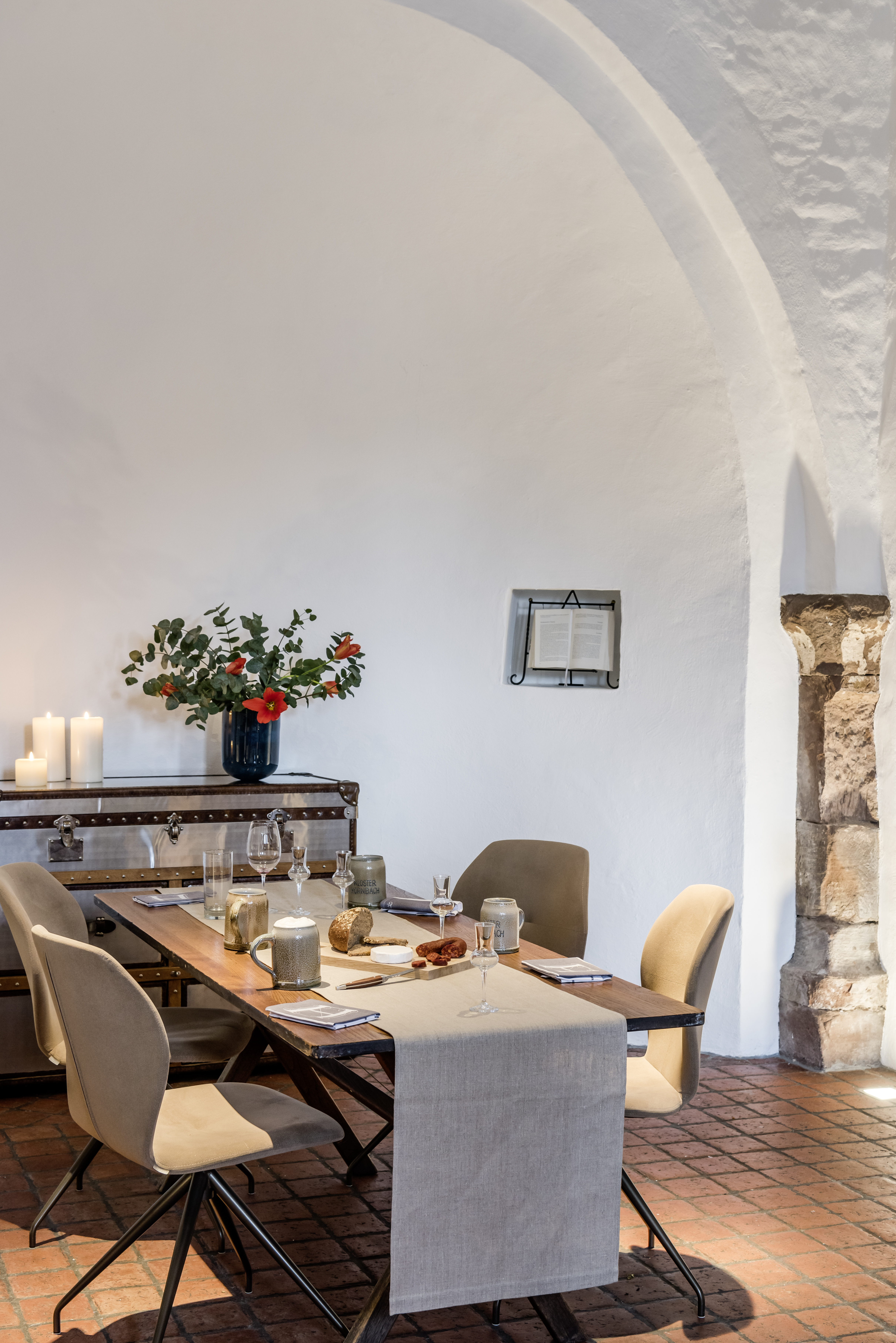 Moderner Essbereich mit Holztisch, beigen Stühlen und Kerzen in einem Raum mit Rundbogen